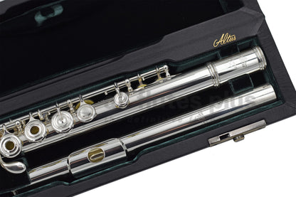 An Altus A12 flute, displayed in an open case with green velvet interior, close up of headjoint and left hand of body joint 