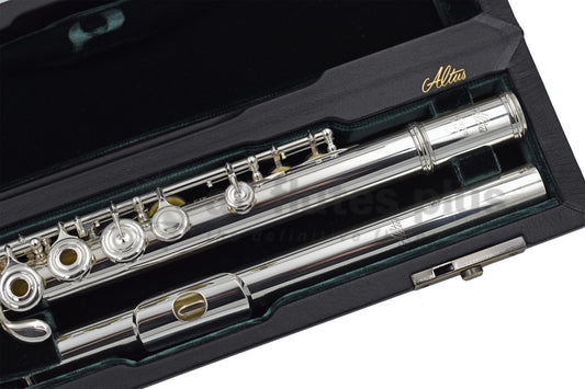 An Altus A12 flute, displayed in an open case with green velvet interior, close up of headjoint and left hand of body joint 