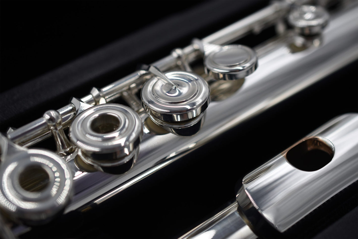 Close-up of a Nagahara silver flute with 14K gold riser, showing the body tube, tone holes, and mechanism.