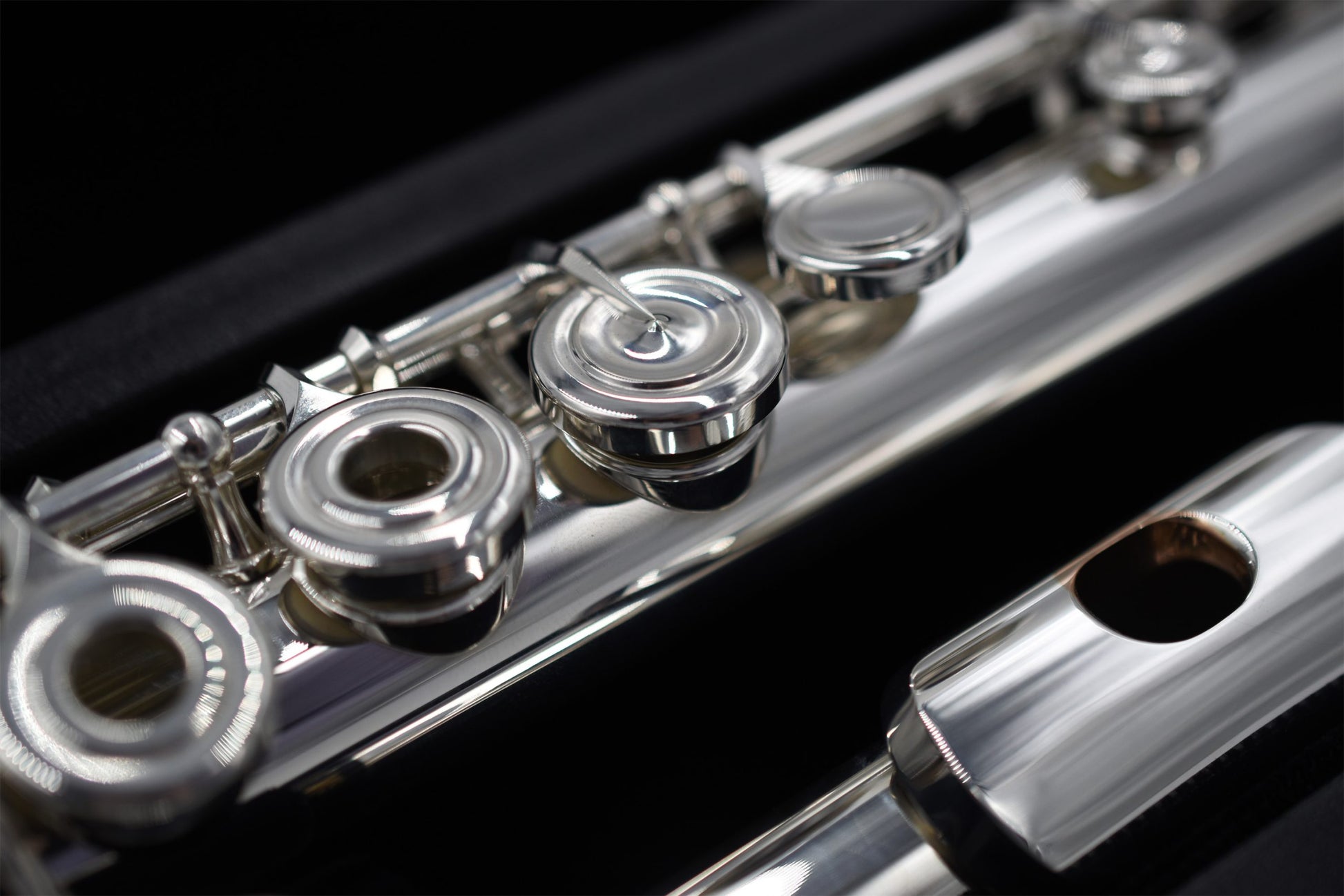 Close-up of a Nagahara silver flute with 14K gold riser, showing the body tube, tone holes, and mechanism.