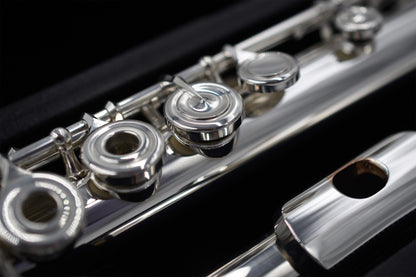 Close-up of a Nagahara silver flute with 14K gold riser, showing the body tube, tone holes, and mechanism.