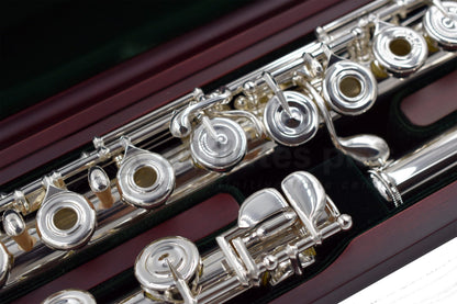 Close up of Pearl PF 695RE Flute set in a cherrywood open case showing body tube and footjoint mechanism