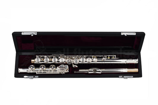 A Trevor James Performers Privilege Flute with open holes, silver-plated body, and key arms, displayed alongside its French-style wooden case with a black exterior and velvet lining.